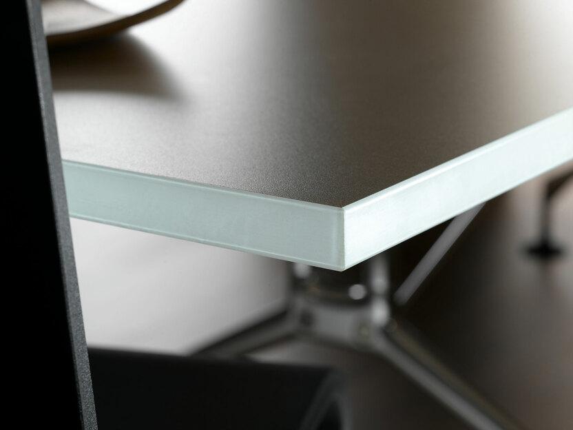 Detailaufnahme eines Arbeitstisches mit schwarzer Oberfläche und weißer Außenkante