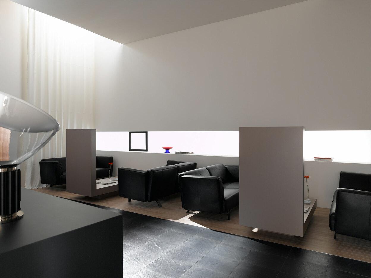 Hotellobby mit Trennwänden aus Holz und schwarzen Ledersofas