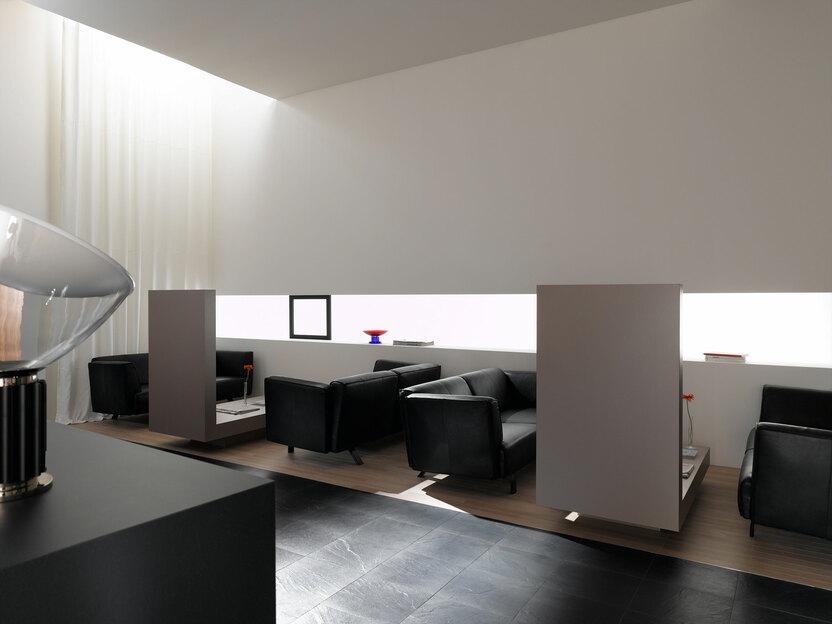 Hotellobby mit Trennwänden aus Holz und schwarzen Ledersofas