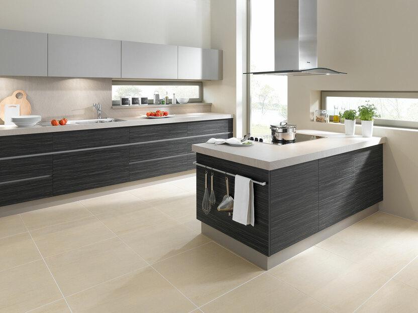 Impression einer Küchengestaltung mit Kochinsel mit Edelstahlabzug und dunklen Fronten