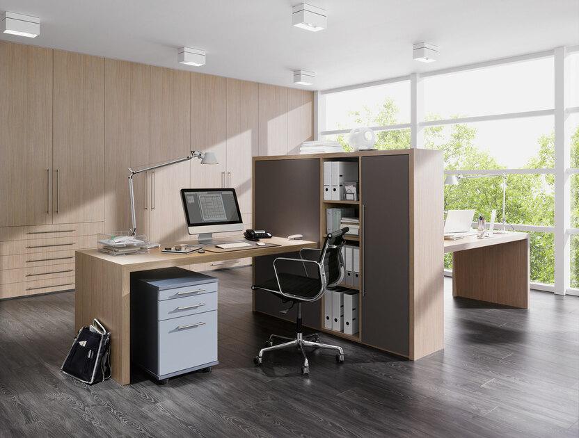 Impression von freistehenden Büromöbeln in L-Form mit hellem Einbauschrank im Hintergrund