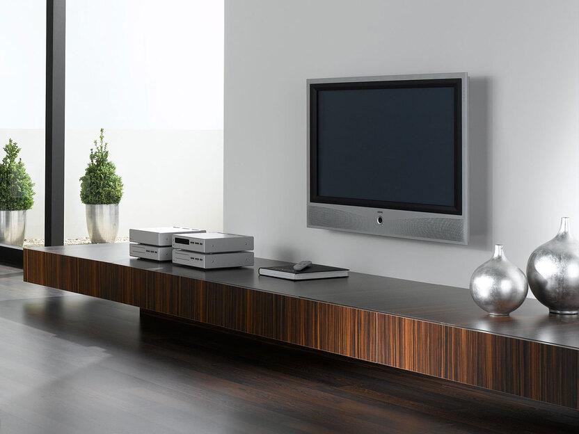 Wohnraumimpression mit verschieden dunklen Holzoberflächen für Einbauschrank, Sideboard und Bodenbelag